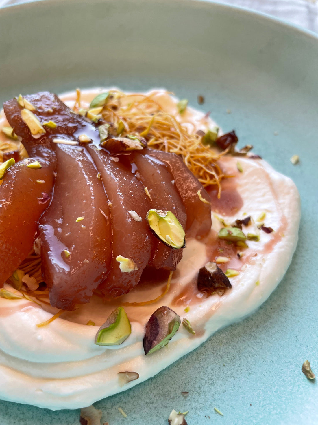 sliced red wine poached pear on top of whipped mascarpone cream and a bed of crispy kadaifi nest with chopped pistachios on top.   